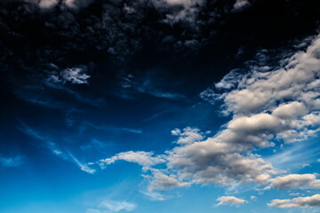 Obraz na płótnie Canvas white shaded gray clouds floating calmly in a gradient blue sky.
