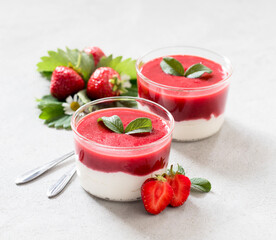 Dessert cream cheese with strawberry sauce in a glass Cup on a light background