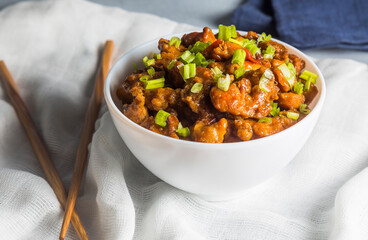 Orange chicken sliced ​​into small pieces. This dish is decorated with chives. This is one of the quintessential Chinese dishes.