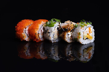 sushi rolls isolated on  black background, food reflection in  glass, japanese food, set with salmon, vegetables, flying fish caviar and caviar close-up.