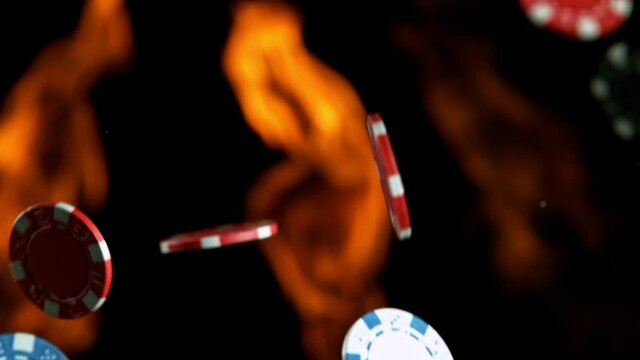 Poker chips with fire flames falling on casino table in super slow motion, filmed on high speed cinema camera at 1000 fps. Gambling background.