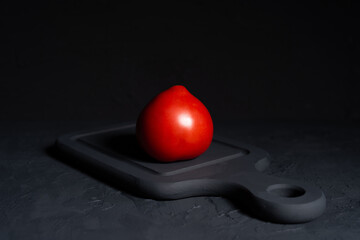 beautiful bright red tomato lies, ripe vegetable on  black background, proper nutrition