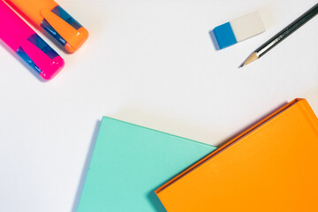 Office or school related object on a white background: coloful notebooks, highlighters, rubber, pencil