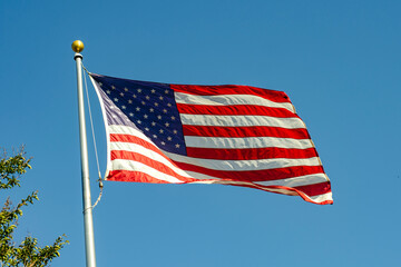 Obraz premium American flag waving in the wind against blue sky, California