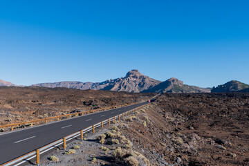 A long road between volcanoes, craters and mountain peaks on the teide on the island of tenerife in spain with clear blue skies