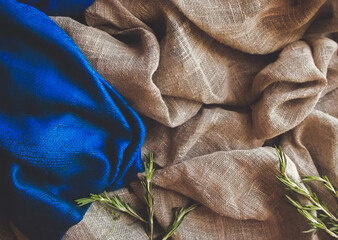 Brown rustic raw sackcloth, blue fabric and fresh green Italian rosemary herb grass spice branches....
