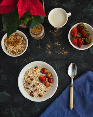 White bowl of oats and strawberries overview in a dark background