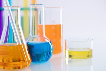 Closeup shot of different flasks with colorful liquids on a white background in a lab
