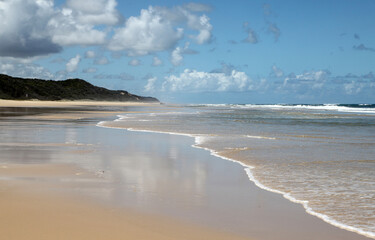 Beautiful image of Fraser Island along 75 miles beach showing blue sky, sand, water and waves