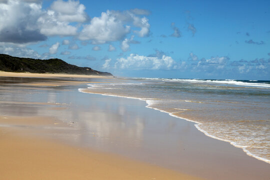 Beautiful image of Fraser Island along 75 miles beach showing blue sky, sand, water and waves
