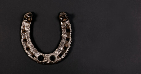 Iron old horseshoe with a soft shadow on a black background. Symbol of good luck and happiness