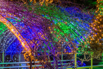 Colorful Christmas lights over park bench.