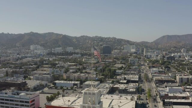 Aerial, reversed footage of an american flag on the wind with Hollywood in the background