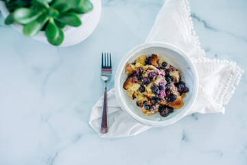 A serving of homemade baked Blueberry crumble cobbler in a ceramic white bowl with a fork
