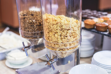 Decorated breakfast catering setting at the hotel, with variety of dishes: cereal, corn flakes, vegetables, toast, pancakes, pastry, cupcakes and other food