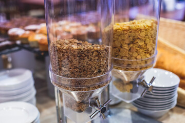 Decorated breakfast catering setting at the hotel, with variety of dishes: cereal, corn flakes, vegetables, toast, pancakes, pastry, cupcakes and other food