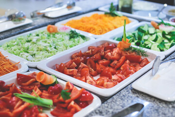 Decorated breakfast catering setting at the hotel, with variety of dishes: cereal, corn flakes, vegetables, toast, pancakes, pastry, cupcakes and other food
