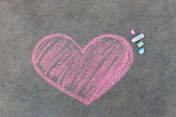 pink heart drawn with chalk on asphalt. Symbol of love drawn on the pavement.