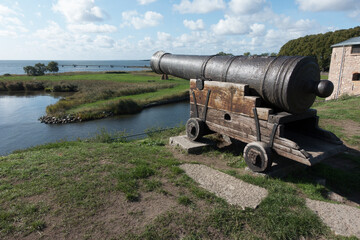 Wooden and rusty medieval cannon at a fort close to the sea.