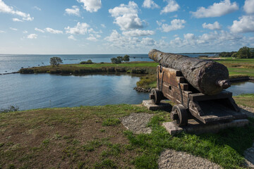 Wooden and rusty medieval cannon at a fort close to the sea © David