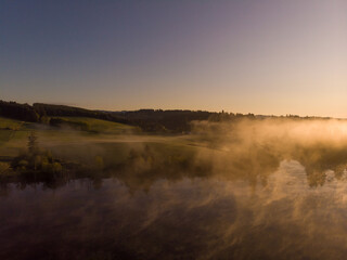 Fototapeta na wymiar Sunset or dawn on a morning lake or swamp, steam and haze