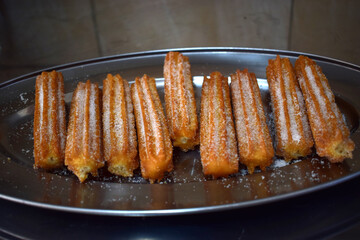 Churros with sugar in metal tray
