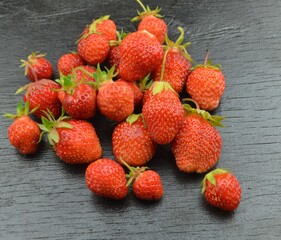 
self-grown strawberries lie on a black wooden background
