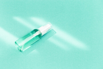 Small bottle with transparent cosmetic product, gel or crem on mint colored background. Flack with moisturizer for self-care. Monochrome image.