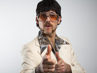 Portrait of a retro man in a 1970s leisure suit and sunglasses pointing to the camera - obrazy, fototapety, plakaty