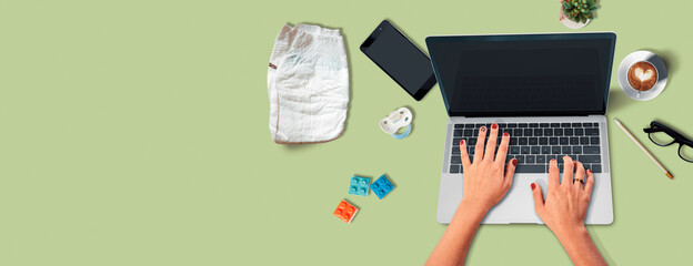 Persona que usa computadora mientras tiene en su mesa juguetes de niño, un chupete, un celular y...