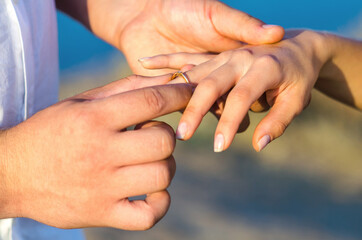 She said YES. Young man puts a wedding ring on the finger of his bride