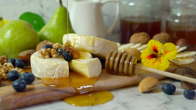Camembert and brie cheese board with honey, fruit and nuts.