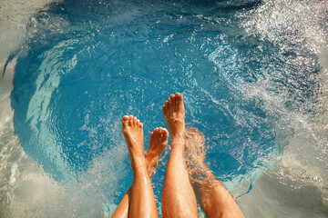 Male and female legs in the swimming pool. Young relaxed couple in jacuzzi. Spa.