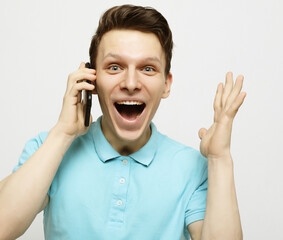 Happy young man in shirt gesturing and smiling while talking on the mobile phone