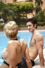 Man and woman talking while relaxing by the poolside