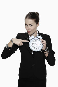 Businesswoman pointing at alarm clock