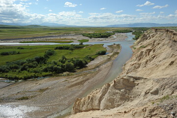 A valley with a mountain river and grazing animals. Territory near the Khan Tengri mountain range.