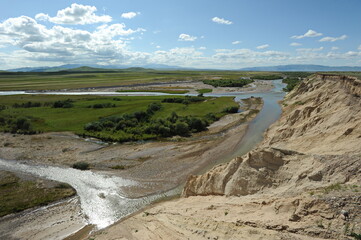 A valley with a mountain river and grazing animals. Territory near the Khan Tengri mountain range.