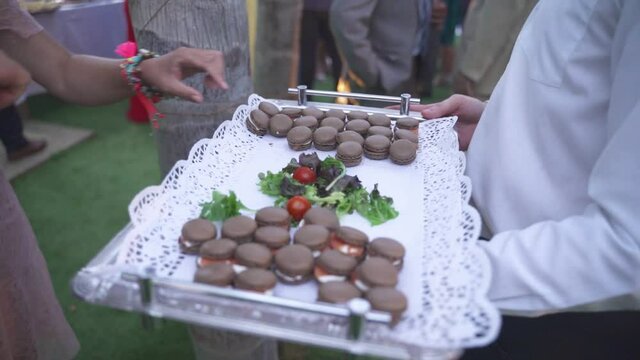 Guest picking up a dessert from a tray during a formal outdoors event