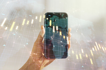 Double exposure of abstract creative financial diagram with world map and hand with cellphone on background, banking and accounting concept