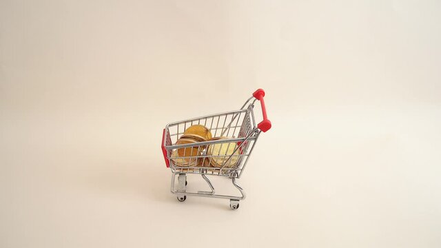 Hand pushing a shopping cart full of coins. Business concept.