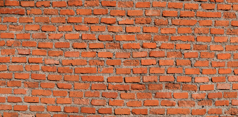 The red brick wall, rough and irregular background.