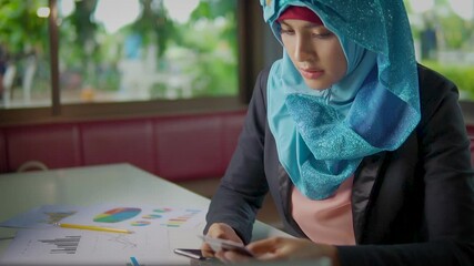 Young Islam woman in hijab entering credit card number on smartphone shopping online at home. - Powered by Adobe