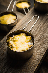 Julienne with chicken, cheese and mushrooms served in small metal bowl. Selective focus. Shallow depth of field.