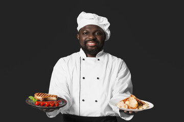 Male African-American chef with tasty dishes on dark background