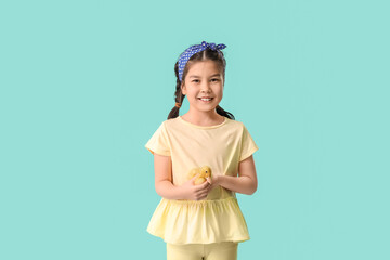 Little girl with cute duckling on color background