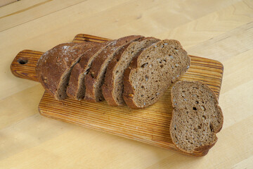 Sliced rye bread lies on a wooden board, ready to eat.