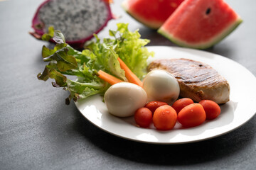 Boiled eggs, grill chicken breast and vegetable on black table. Healthy breakfast concept.