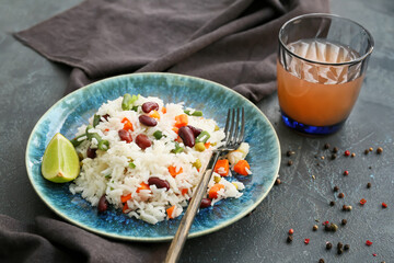 Plate with tasty rice, beans and vegetables on dark background