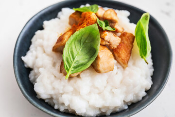 Bowl with boiled rice and chicken on white background, closeup